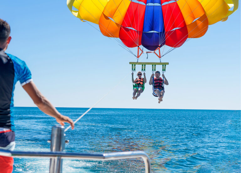 a couple paragliding behind a boat