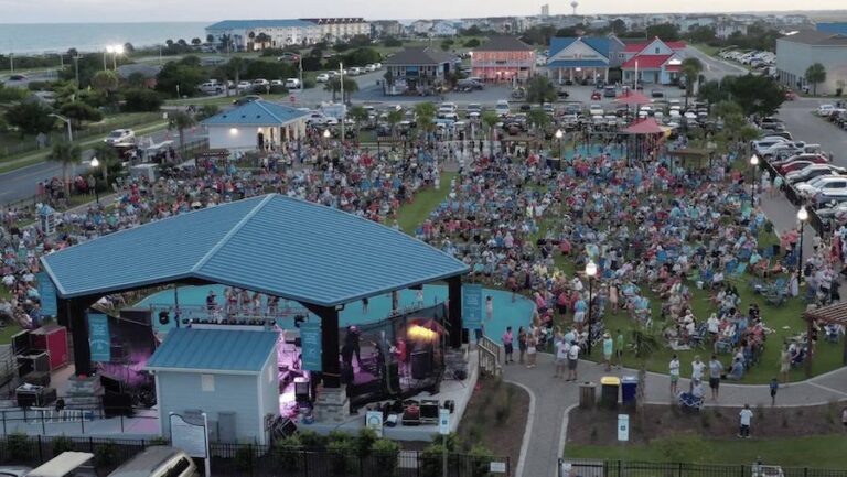 Aerial view of a crowd gathered in front of the outdoor stage at an Ocean Isle Beach festival, with the beach and ocean behind